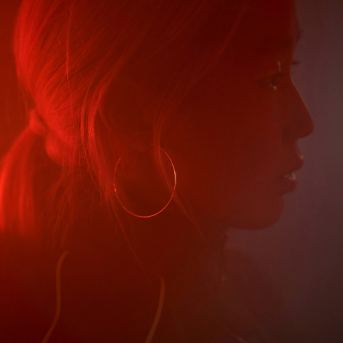 Red coloring over a side profile of a female with her hair pulled back. 